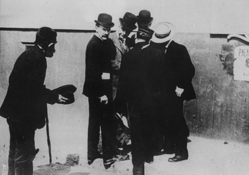 US industrialist and philanthropist John Davison Rockefeller (1839 - 1937) (centre), in conversation with fellow businessmen, ignores an old beggar