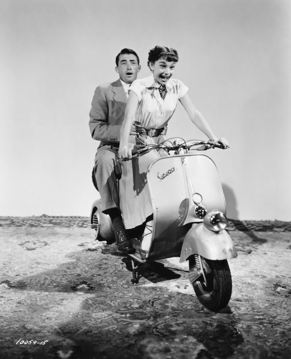 Gregory Peck and Audrey Hepburn practice a moped scene for the 1953 comedic romance Roman Holiday, in which Peck plays the role of journalist Joe Bradley and Audrey Hepburn as Anya Smith, aka Princess Ann, who has run away from her life of royalty. (Photo by �� John Springer Collection/CORBIS/Corbis via Getty Images)