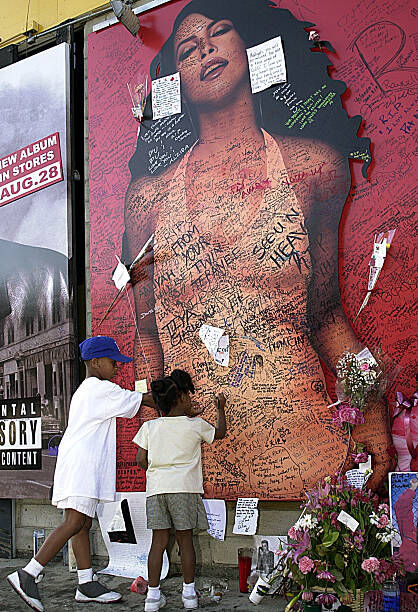 Fans of R&B singer/actress Aaliyah sign a record store mural of the late singer in what has become a shrine dedicated to her after her death in a plane crash in the Bahamas. (Photo by Steve Grayson/WireImage)